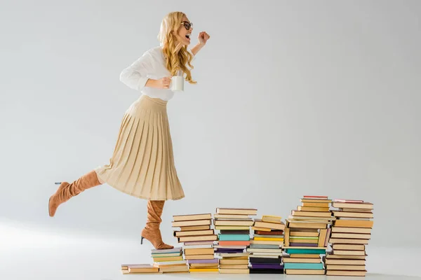 Mulher elegante adulto de pé em livros com caneca branca — Fotografia de Stock