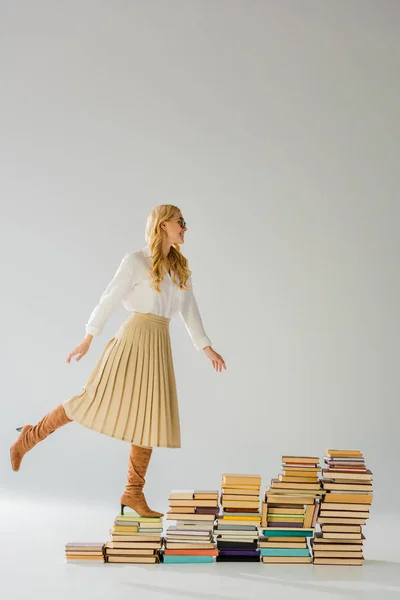 Приваблива доросла жінка позує на купу ретро-книг — стокове фото