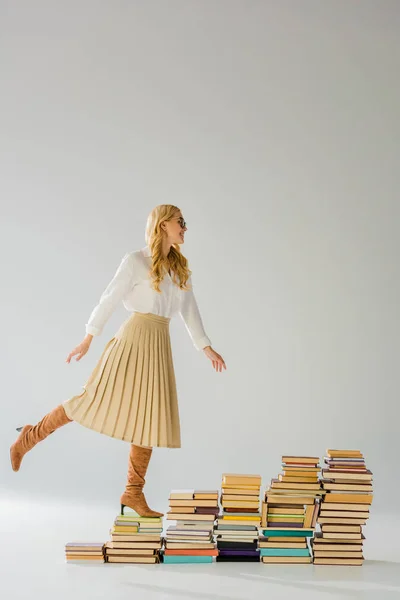 Attractive adult woman posing on pile of retro books — Stock Photo