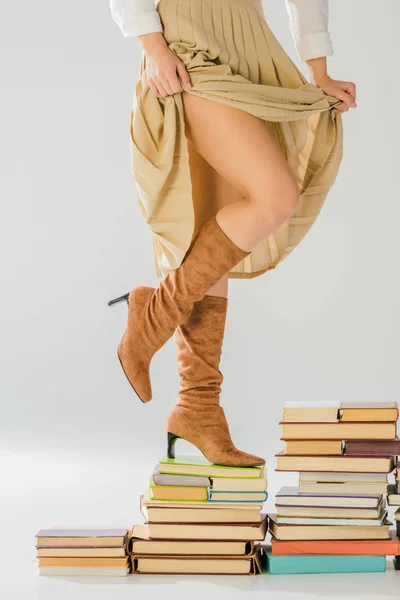 Nahaufnahme einer Frau in Stiefeln, die auf alten Büchern wandelt — Stockfoto