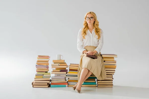 Bella donna adulta seduta su mucchio di libri retrò — Foto stock