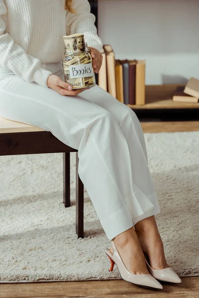 Nahaufnahme einer Frau, die ein Glas mit Geld und Büchern in der Hand hält — Stockfoto