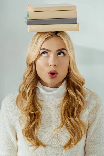 Крупным планом взрослая женщина со смешным выражением лица и книгами на голове — стоковое фото