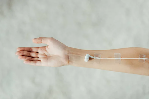 Close up of female hand with white earphone like medical IV infusion, music concept — Stock Photo