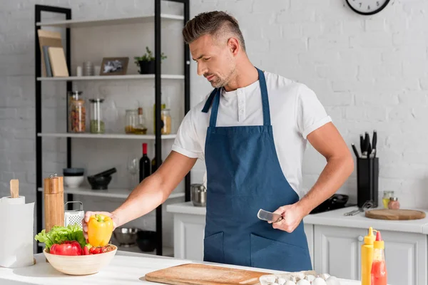 Bell'uomo in grembiule che cucina in cucina a casa — Foto stock