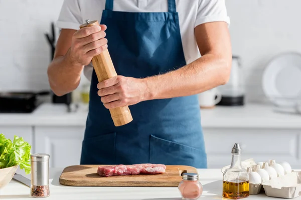 Обрізаний вид чоловіка приправляє м'ясо на вечерю — стокове фото