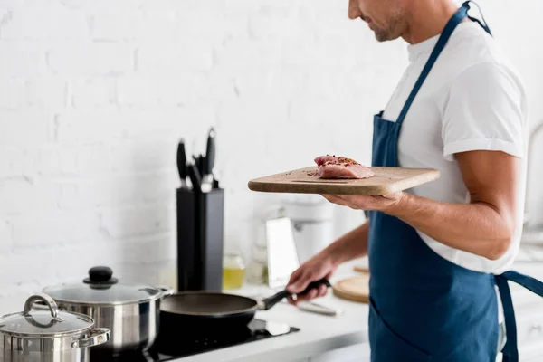 Erwachsener Mann steht mit Pfanne und frischem Steak auf Küche — Stockfoto