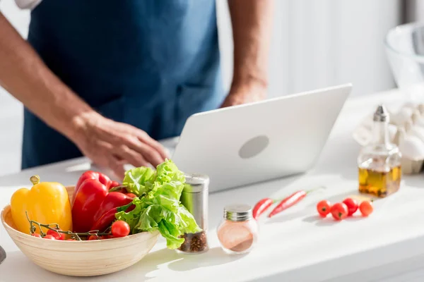 Teilansicht eines Mannes, der am Laptop auf weißem Küchentisch arbeitet — Stockfoto