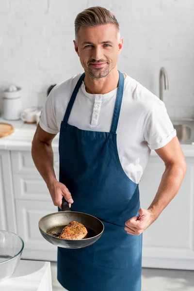 Взрослый мужчина показывает большие пальцы со стейком на сковороде — стоковое фото