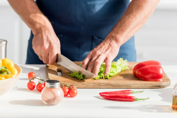 Partial view of man cutting lettuce on chopping board for salad — Stock Photo