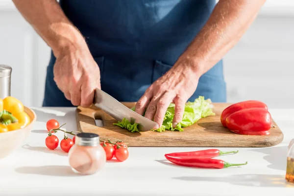 Vista parziale dell'uomo taglio lattuga sul tagliere per insalata — Foto stock