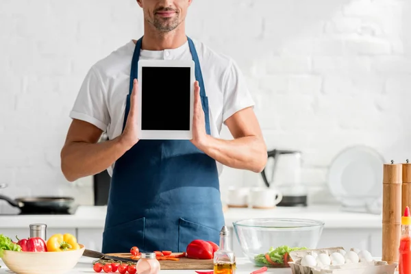 Uomo in grembiule con tavoletta digitale in mano in cucina — Foto stock