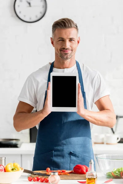 Hombre adulto sosteniendo tableta digital con pantalla en blanco en la cocina - foto de stock