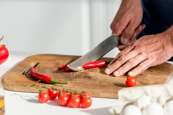 Vista de perto de mãos masculinas cortar pimentas na tábua de corte — Fotografia de Stock