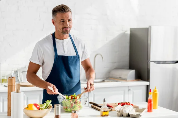 Adult man preparing salad at kitchen table — Stock Photo