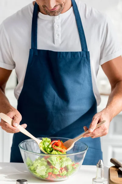 Vista ritagliata di uomo miscelazione insalata in cucina — Foto stock