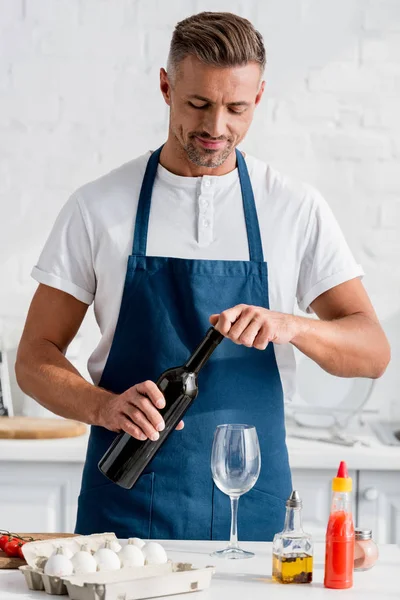 Hombre adulto apertura botella de vino en la cocina - foto de stock