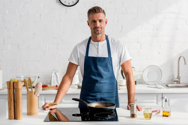 Adult man frying steak on pan at kitchen — Stock Photo