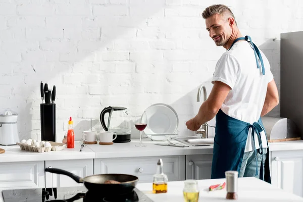 Adult man washing dishes at kitchen — Stock Photo