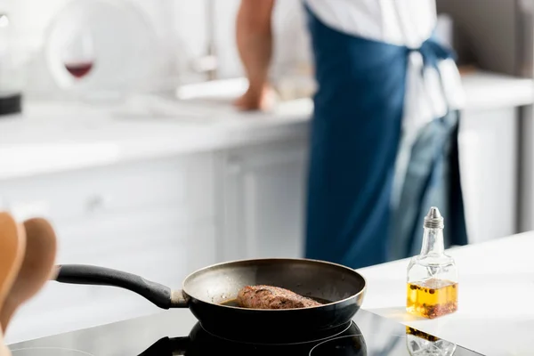 Крупним планом вид стейка на сковороді і пляшку олії — стокове фото