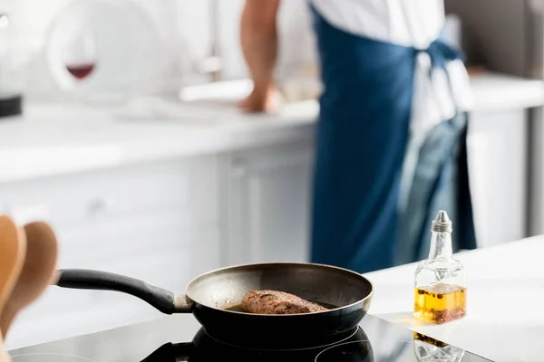 Vue rapprochée du steak sur la casserole et la bouteille d'huile — Photo de stock