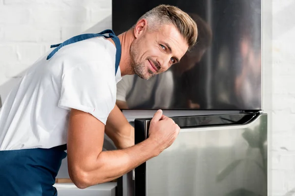 Adult man opening shiny silver fridge door — Stock Photo