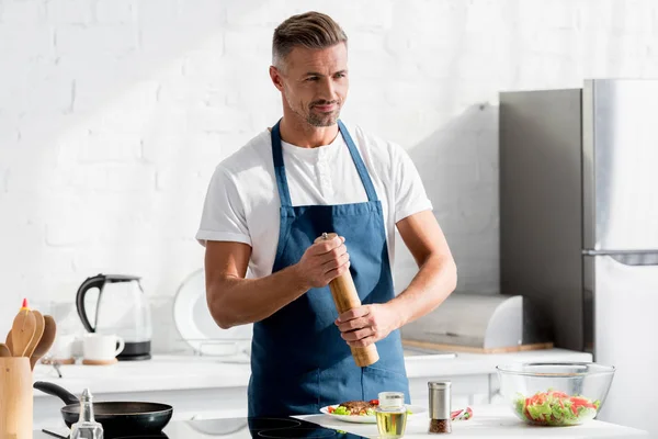 Adult man with salting cooked steak with vegetables — Stock Photo