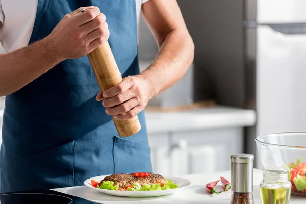 Cropped view of man salting steak with salt mill — Stock Photo