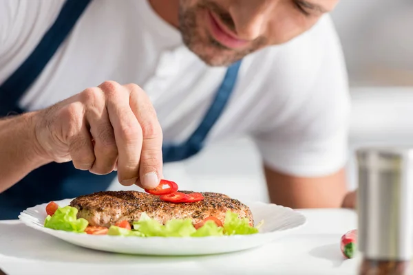 Nahaufnahme eines erwachsenen Mannes, der dem gekochten Steak Pfeffer hinzufügt — Stockfoto