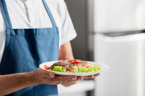 Vista recortada del hombre con filete cocido y verduras en el plato - foto de stock