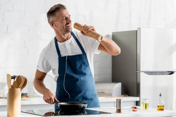 Bell'uomo in cuffia con padella e mulino a sale che canta in cucina — Foto stock