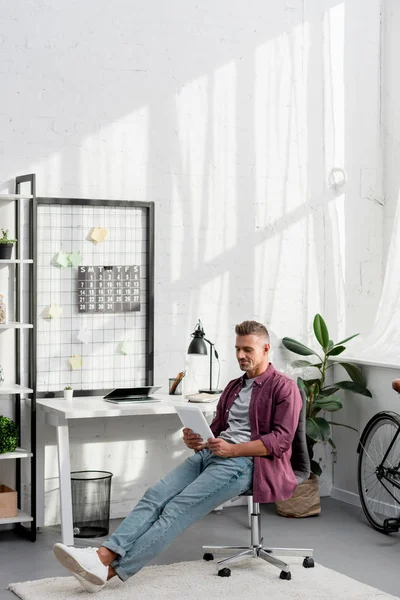 Hombre relajante sentado en la silla con la tableta digital - foto de stock