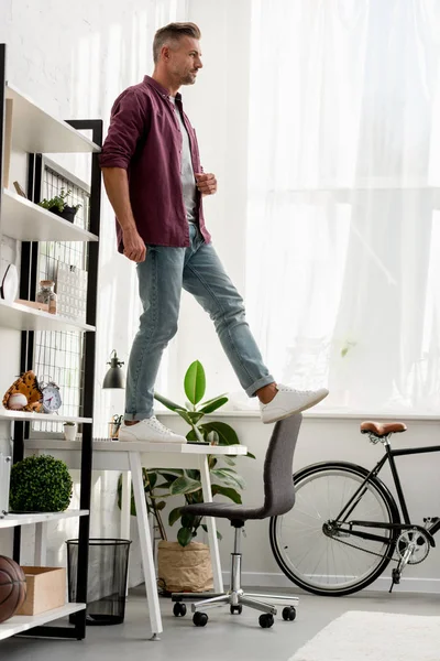 Man stepping off table at home office — Stock Photo