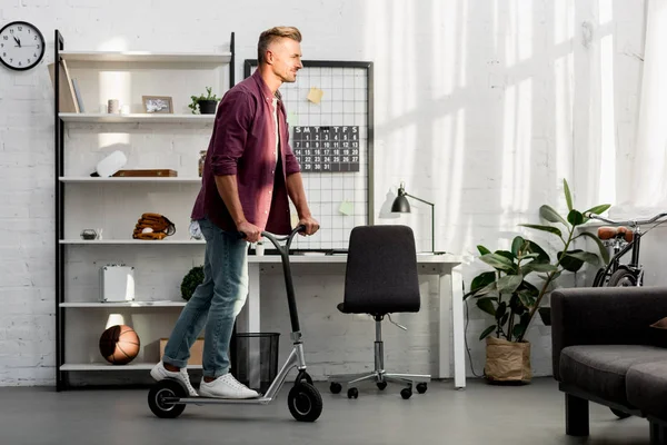 Homem bonito montando scooter em casa escritório — Stock Photo