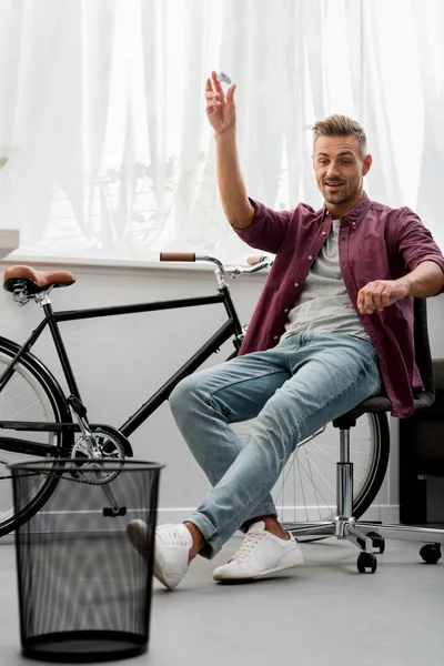 Smiling adult man throwing trash in basket — Stock Photo