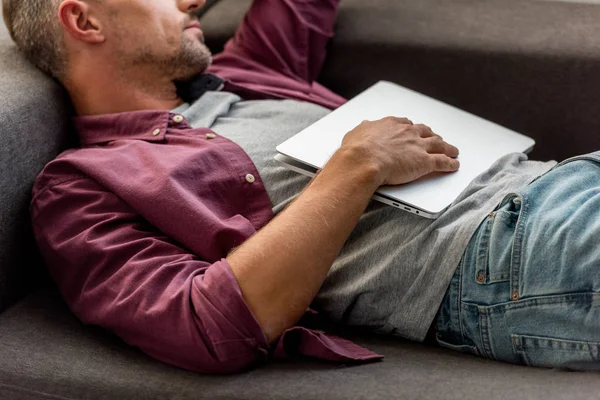 Close up of man laying on sofa with laptop and sleeping at home office — Stock Photo