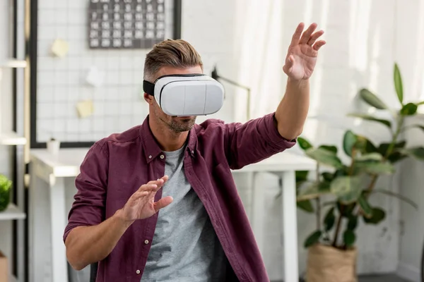 Homem gesticulando em realidade virtual headset no home office — Fotografia de Stock