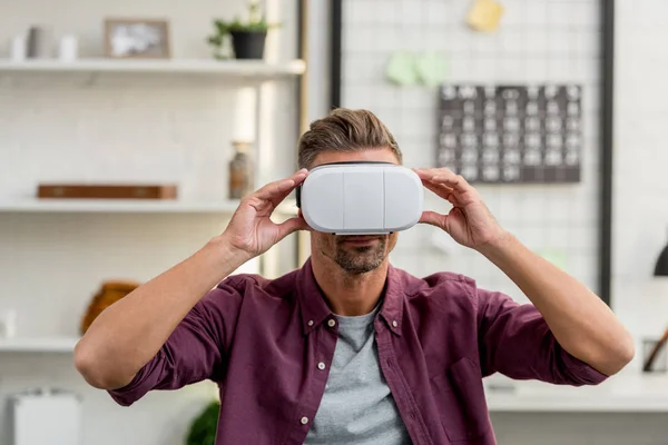 Hombre guapo en auriculares de realidad virtual en la oficina en casa - foto de stock