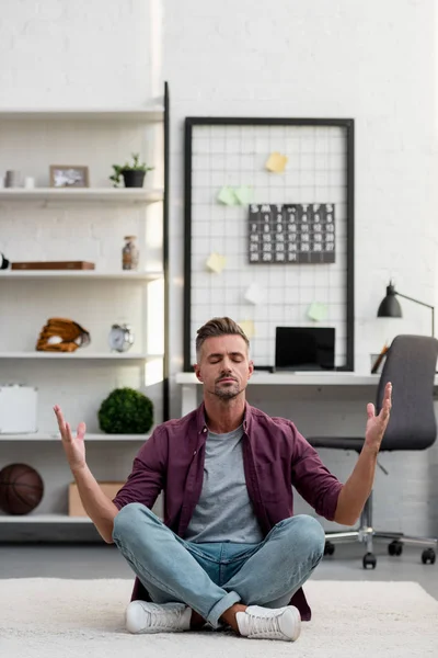 Homem sentado no chão e praticando ioga no escritório em casa — Fotografia de Stock