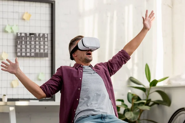 Scared man sitting on chair in virtual reality headset — Stock Photo
