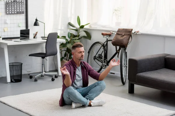 Hombre concentrado sentado en el suelo practicando yoga en casa oficina — Stock Photo