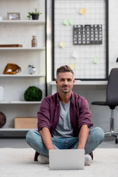 Uomo allegro seduto in ufficio a casa e lavorare sul computer portatile — Foto stock