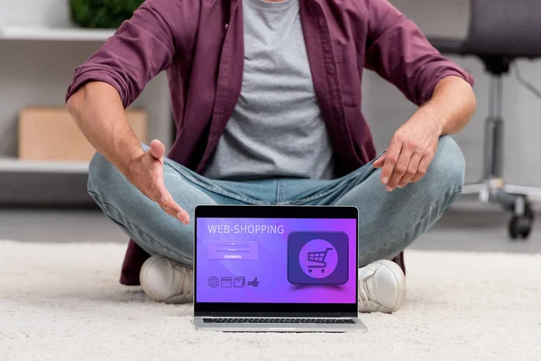 Cropped view of man pointing at laptop with online shopping illustration — Stock Photo