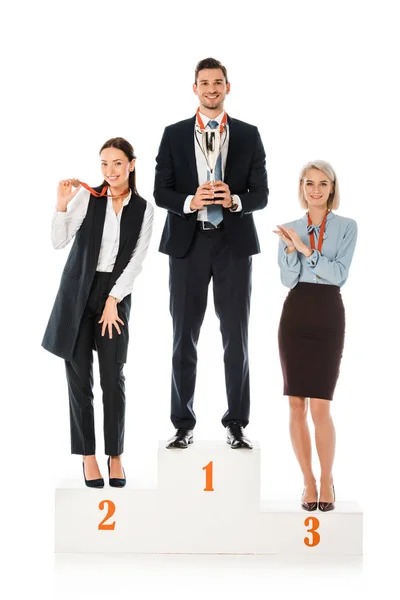 Successful businesspeople holding awards while standing on winners podium isolated on white — Stock Photo