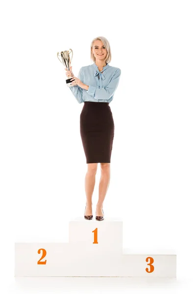 Successful businesswoman with trophy cup standing on winners podium isolated on white — Stock Photo