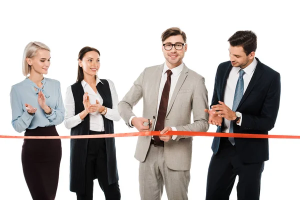 Smiling leader cutting red ribbon for grand opening while colleagues applauding, isolated on white — Stock Photo