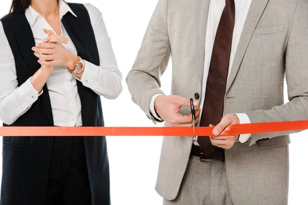 Vista recortada de empresarios cortando cinta roja con tijeras para gran apertura, aislado en blanco - foto de stock