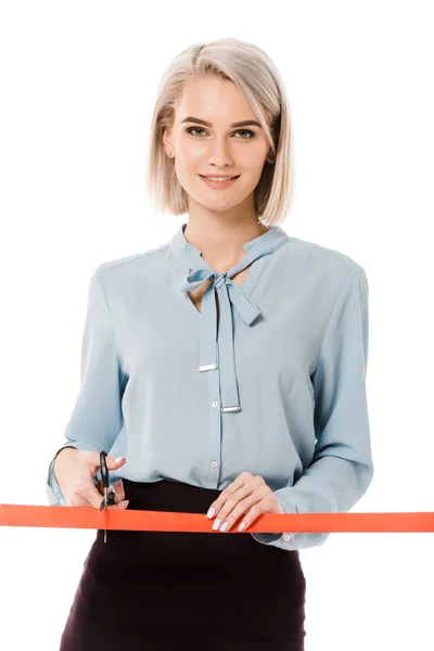 Smiling businesswoman cutting red ribbon with scissors for grand opening, isolated on white — Stock Photo