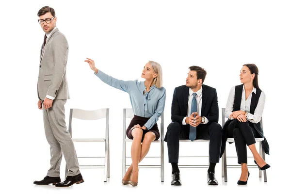 Despedido empresario alejándose de compañeros de trabajo sentados en sillas aisladas en blanco - foto de stock