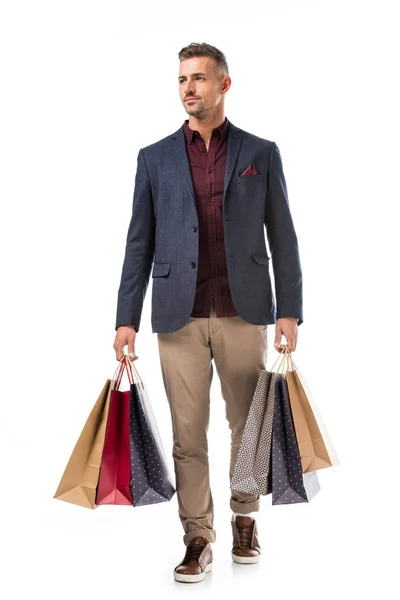 Adult stylish man in jacket holding colorful shopping bags isolated on white — Stock Photo